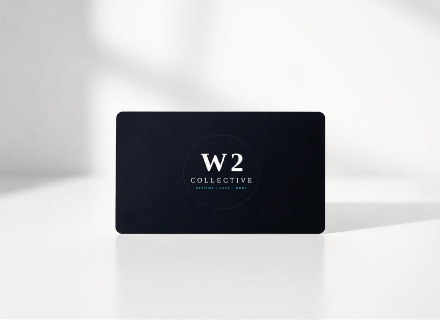 A black W2 Collective NFC business card standing on a white surface